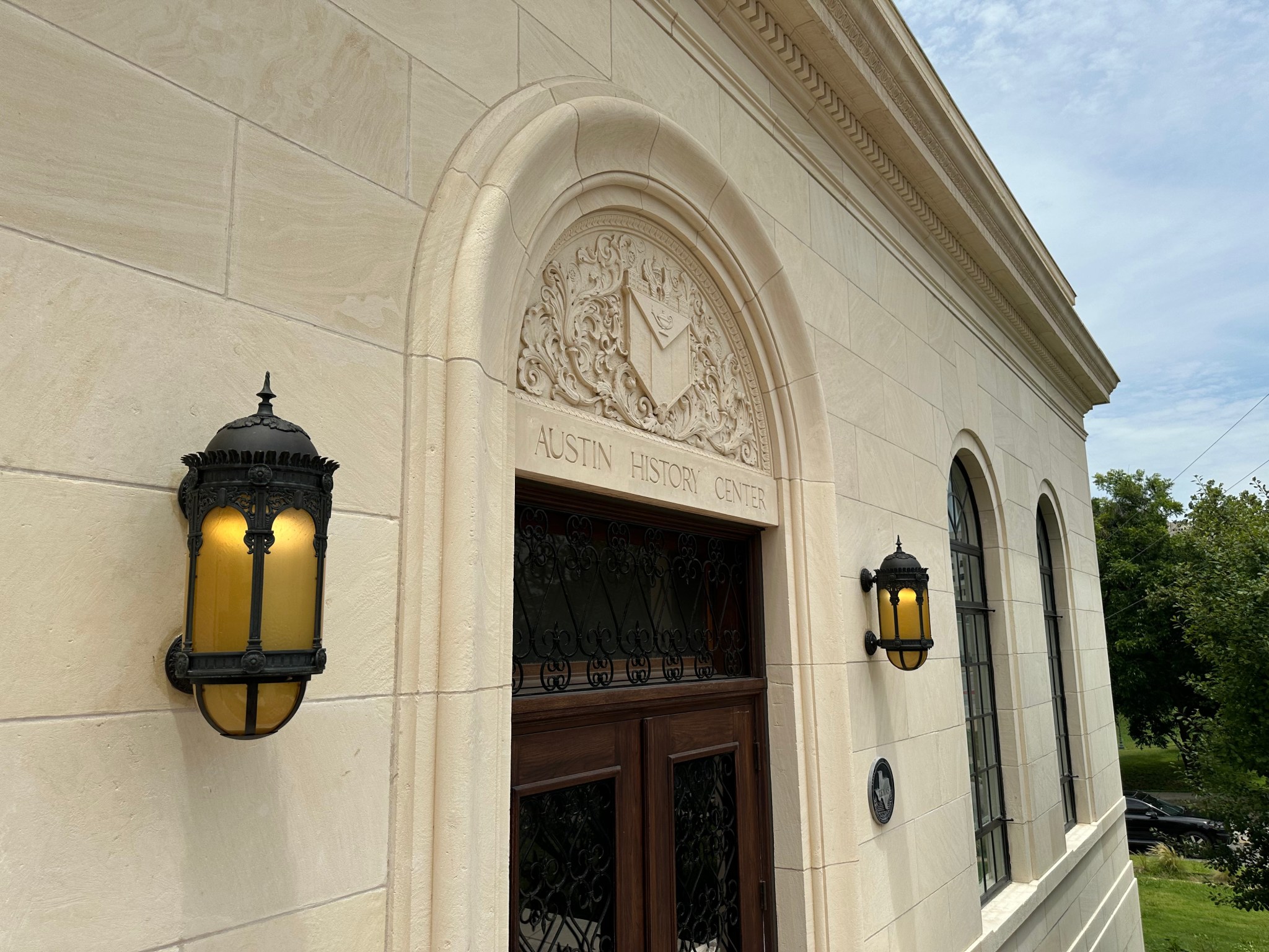 A lantern beside the carved entrance of the 1933 Austin History Center building